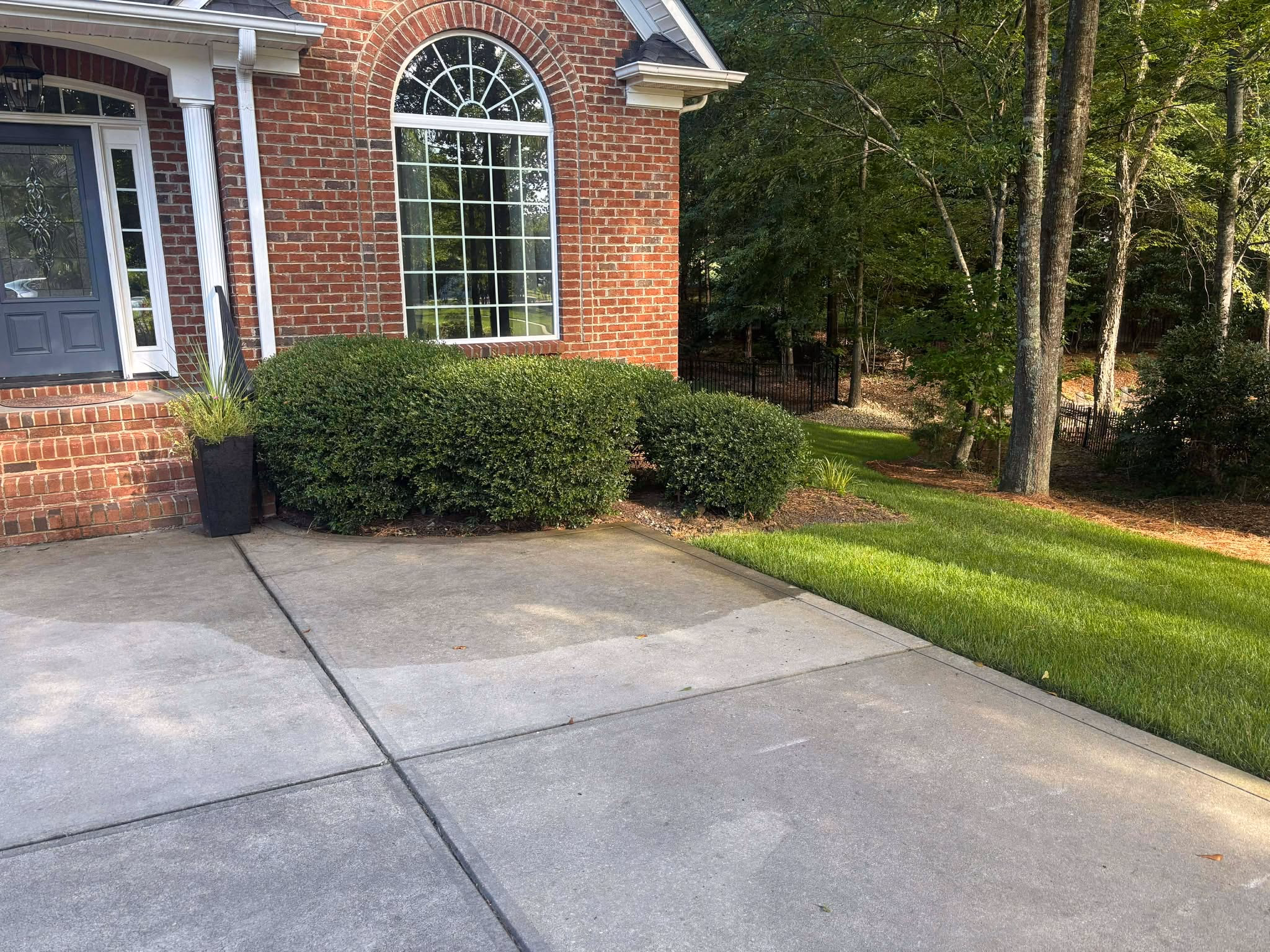 Concrete driveway running the length of a brick home, edged against a mown lawn.