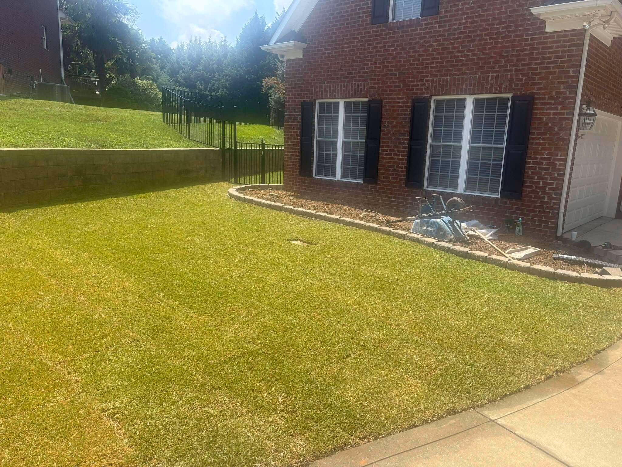The same yard finished with thick green lawn running up to the wall and the walkway.